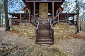 Una cabaña de madera con fachada de piedra, una escalera de madera y un balcón.