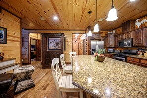 A kitchen with wooden cabinets, granite countertops, and modern appliances. - Yellowstone Lodge: Sleeps 18 + Game Room + Loft (Broken Bow)