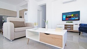 Una sala de estar moderna con sofá, mesa de centro y televisor de pantalla plana mostrando la interfaz de un servicio de streaming.