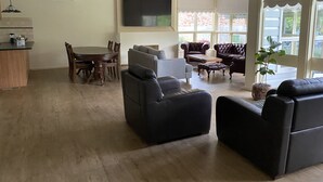 Ein geräumiges Wohnzimmer mit Essbereich, Ledersofas, einem Flachbildfernseher und großen Fenstern.