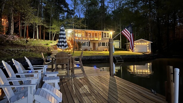 A wooden deck with lounge chairs, a small table, and a flagpole with an American flag. - Peaceful vacation very close to The Landing!! (Equality)