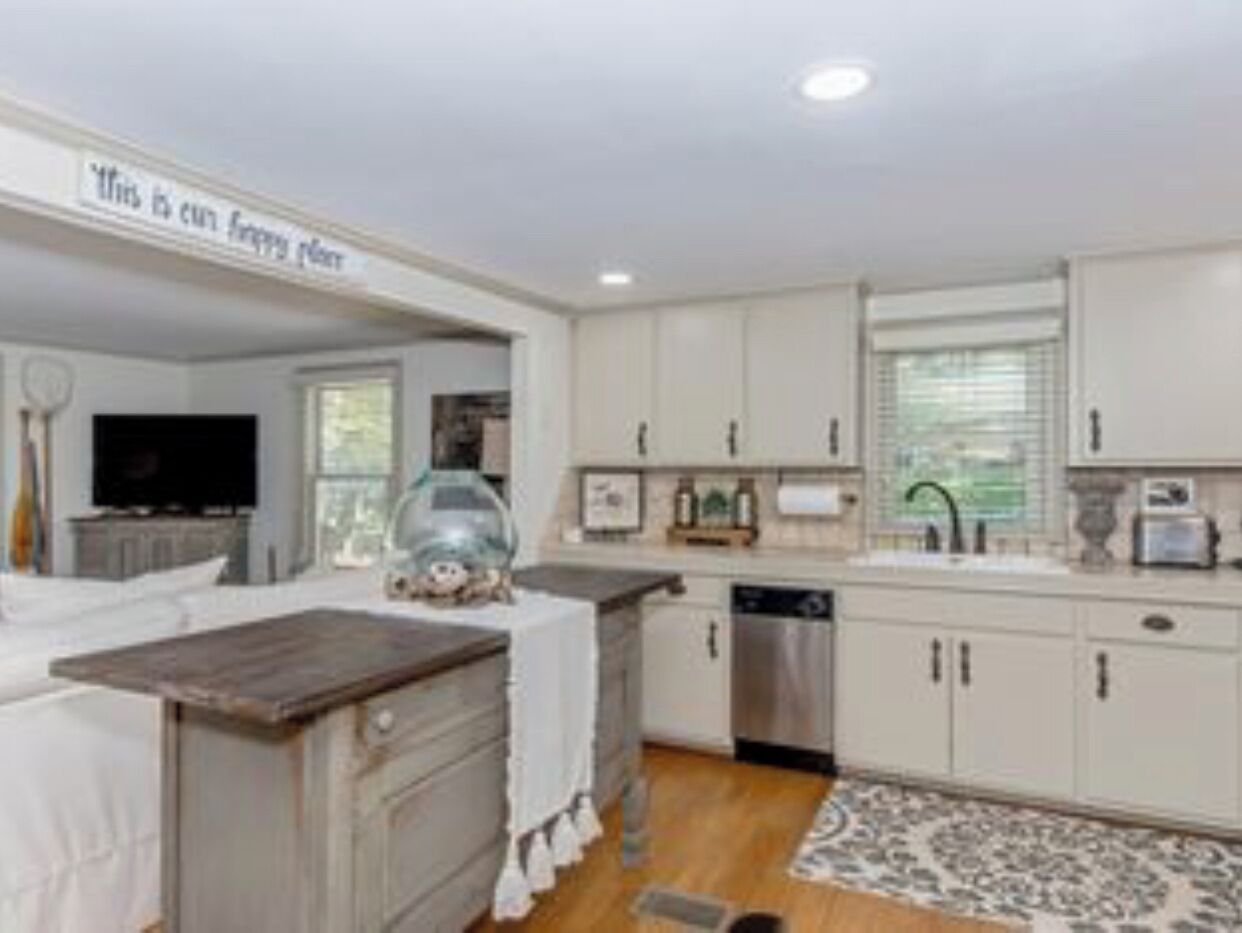 A modern kitchen with white cabinets, a wooden countertop, and a built-in dishwasher.