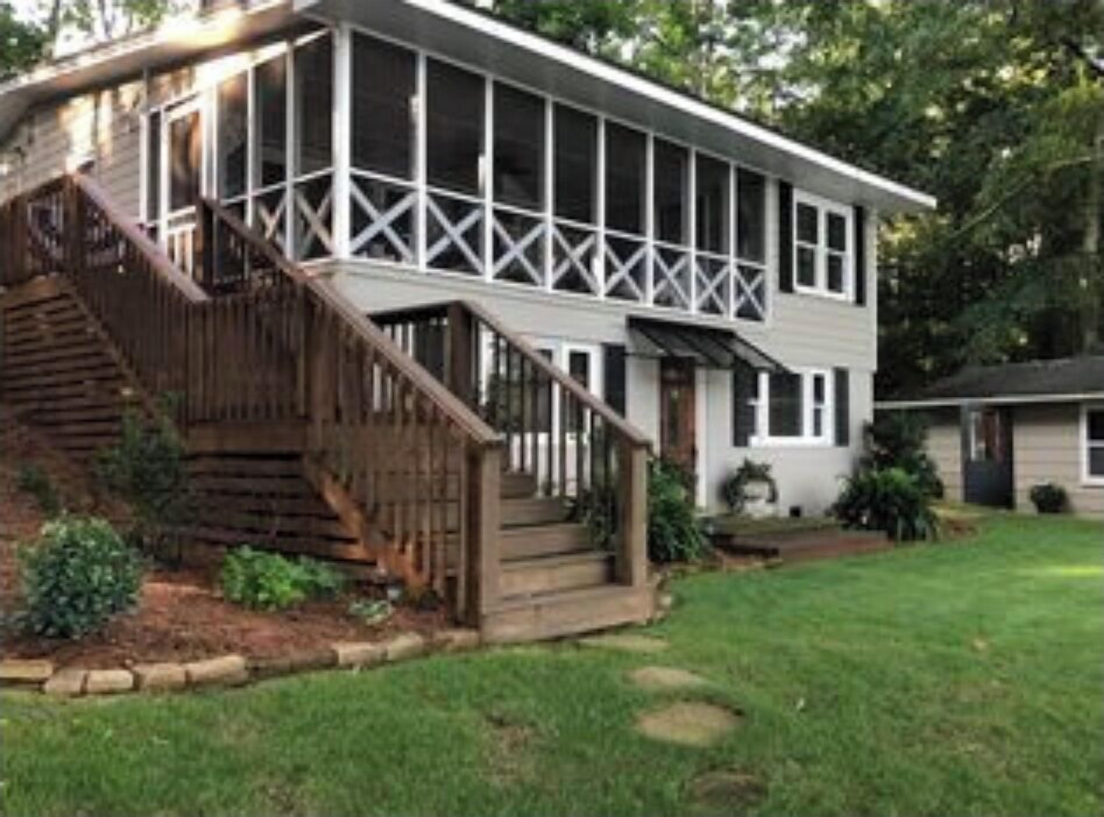 A two-story house with a covered porch and a wooden staircase leading to the entrance.