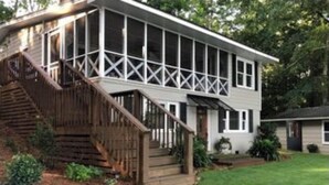 A two-story house with a covered porch and a wooden staircase leading to the entrance. - Peaceful vacation very close to The Landing!! (Equality)