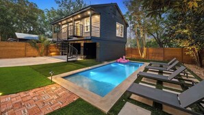Una casa de dos pisos con piscina, un patio cubierto y un patio trasero cercado.