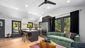 Un espacio moderno para vivir con cocina, sofá verde y zona de bar.