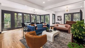 Un salón amplio con un sofá azul, un sillón marrón y una mesa de centro blanca.