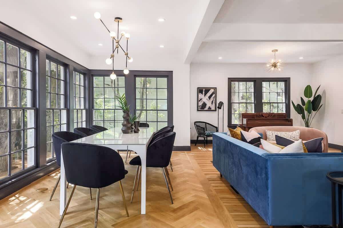 Une pièce spacieuse comprenant une table à manger, des chaises, un canapé et de grandes fenêtres.