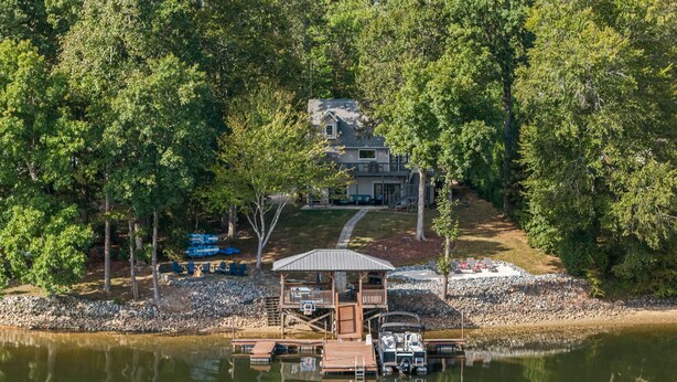 A lakeside property with a dock, a gazebo, and a house surrounded by trees.