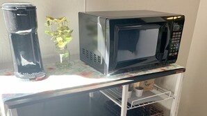 A compact kitchen setup with a microwave, coffee maker, and storage shelves. - Room with mountain views/hiking, private entrance & peaceful courtyard. (Phoenix)