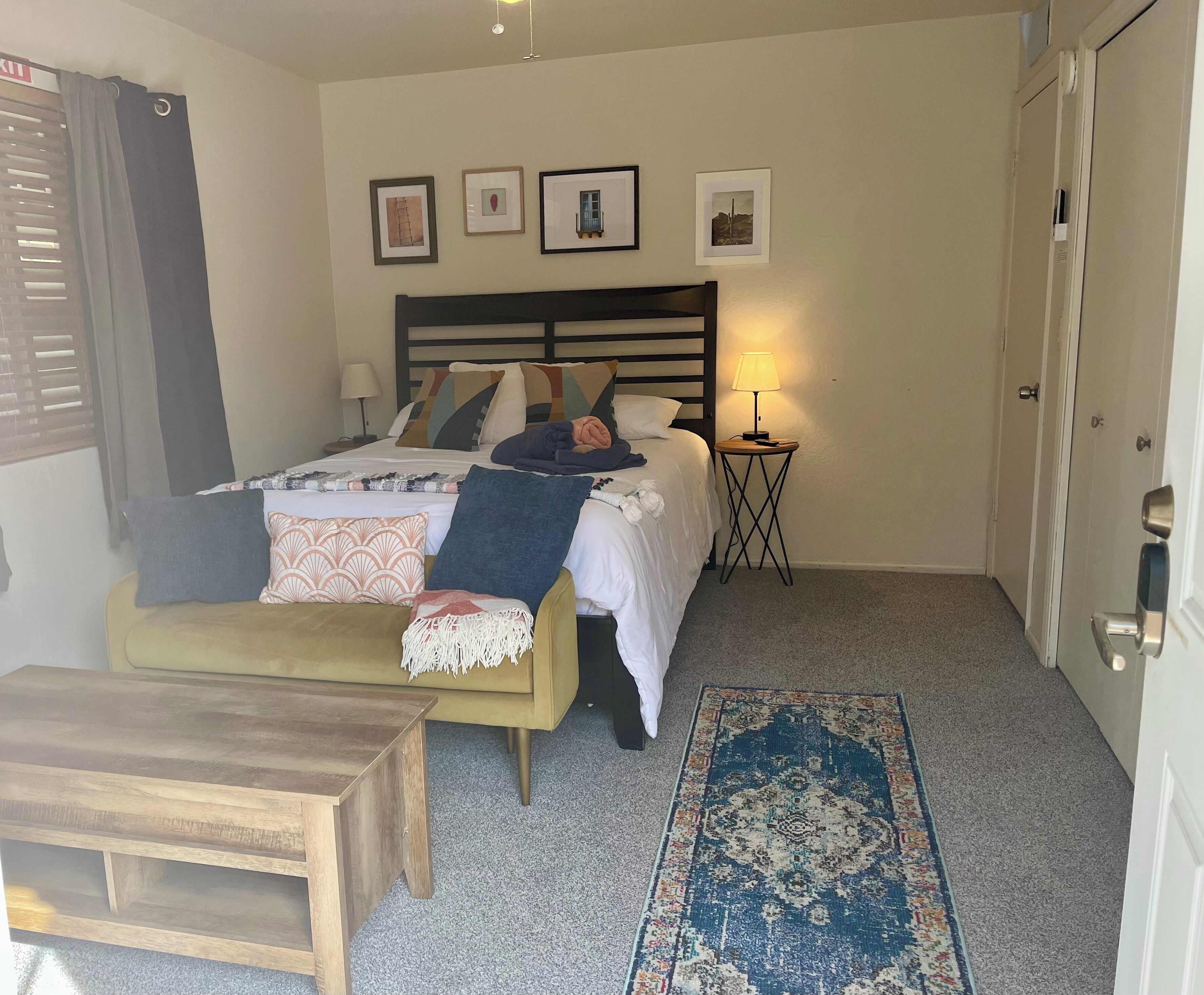 Une chambre à coucher avec un lit, une table de chevet, une lampe et un petit tapis.