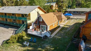 A cabin with a deck, surrounded by other cabins, with a grassy yard and a staircase leading to the deck.