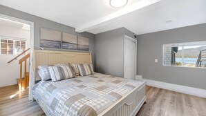 A bedroom with a bed, a window with a view, a door, and a staircase.