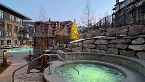Un'area benessere con vasca idromassaggio, pareti in pietra e piscina.