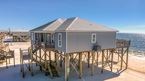 Una casa de playa con balcón, terraza de madera y vista al océano.