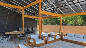 An outdoor patio with wooden furniture, a round table, and a brick wall. - Zion Canyon Retreat - Private Pool & Pickleball Court, Spacious, Clean & FUN!!! (La Verkin)