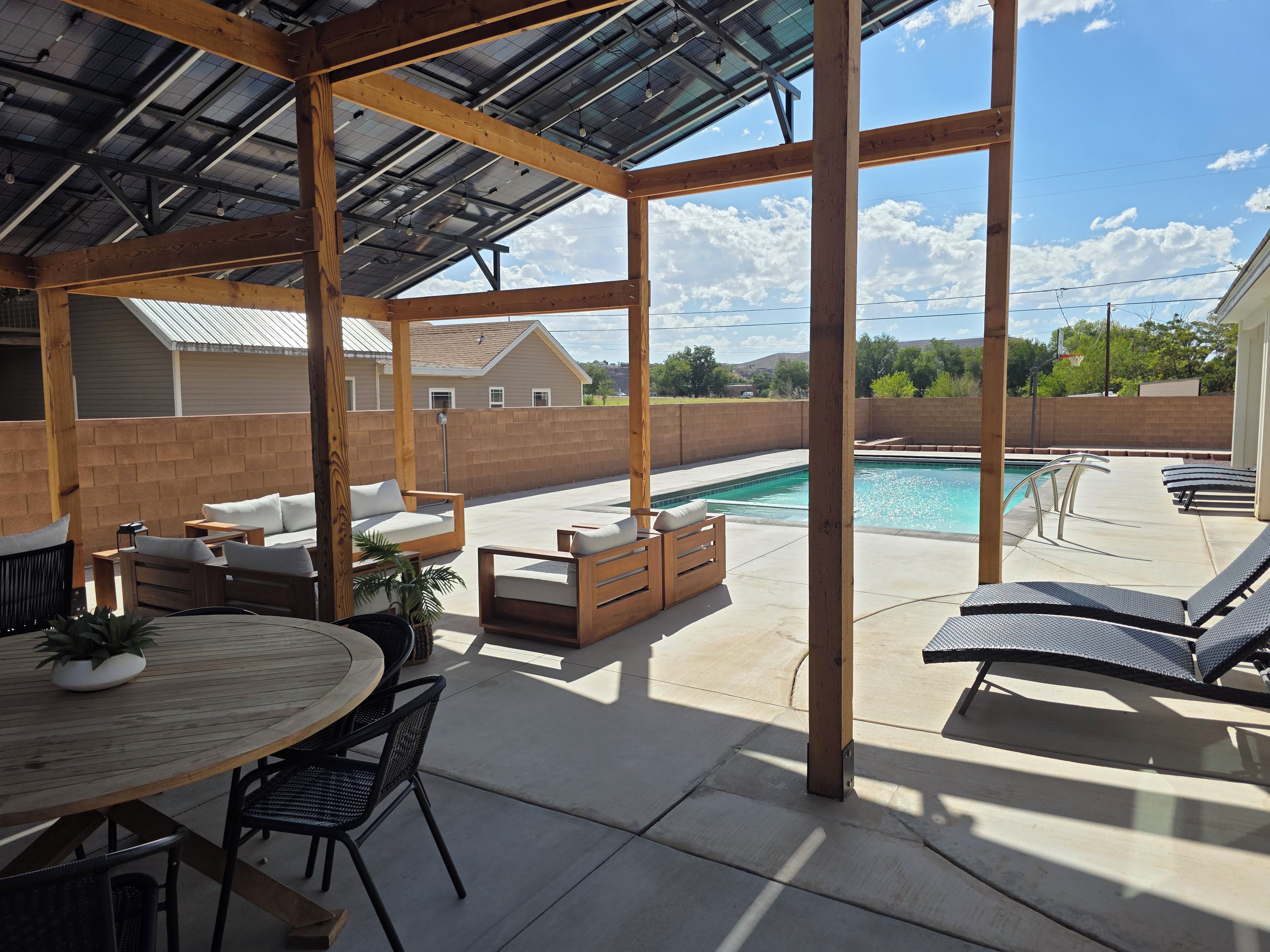 En overdækket terrasse med pool, udendørs møbler og udsigt over det omkringliggende kvarter.