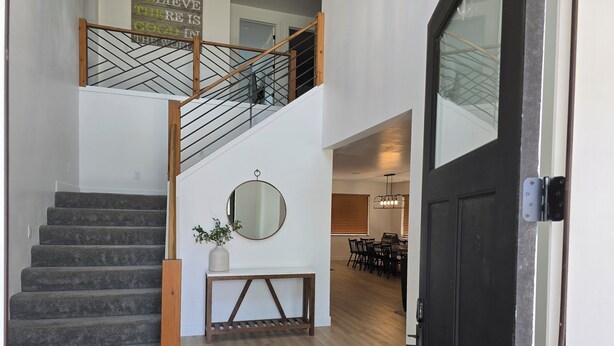 A staircase with wooden railings, a round mirror, and a potted plant on a console table. - Zion Canyon Retreat - Private Pool & Pickleball Court, Spacious, Clean & FUN!!! (La Verkin)