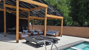 A covered outdoor area with a pool, lounge chairs, and seating arrangements. - Zion Canyon Retreat - Private Pool & Pickleball Court, Spacious, Clean & FUN!!! (La Verkin)