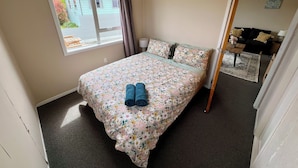 Une chambre à coucher avec un lit, une fenêtre, une porte et une vue sur une maison à l’extérieur.