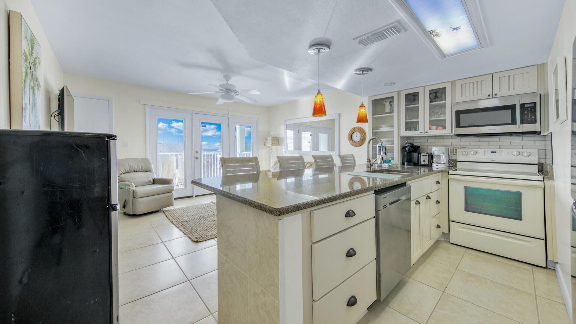 A spacious kitchen with a central island, white cabinetry, and modern appliances.