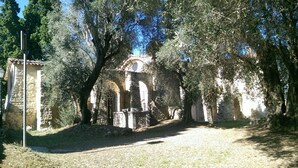 Un'antica costruzione in pietra con porte ad arco, circondata da alberi.