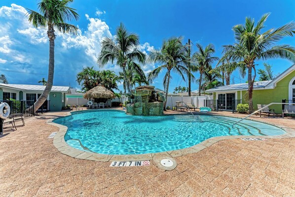 A swimming pool with a 3 ft 7 in depth marker, surrounded by palm trees and lounge chairs.
