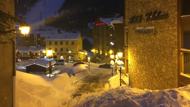 Una calle cubierta de nieve con edificios, incluyendo un hotel llamado "HOTEL SAUDI" y un cartel que dice "MAJESTRE".