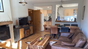 Una sala de estar moderna con chimenea, sofá de cuero, mesa de centro de madera y un comedor con mesa y sillas de madera.