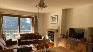 Una sala de estar acogedora con chimenea, una mesa de comedor con velas y un gran ventanal con vistas a un paisaje montañoso.