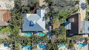 Vue aérienne d’un complexe hôtelier doté de plusieurs piscines, de palmiers et d’un grand bâtiment dont le toit se distingue particulièrement.
