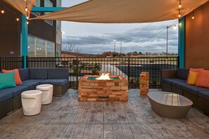An outdoor seating area with a fire pit, sofas, and a coffee table. - Tru by Hilton Tahlequah (Tahlequah)