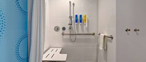 A bathroom with a shower, a towel rack, and a small table.