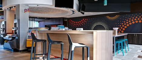 A modern bar area with a counter, bar stools, and a wall with a dotted pattern.