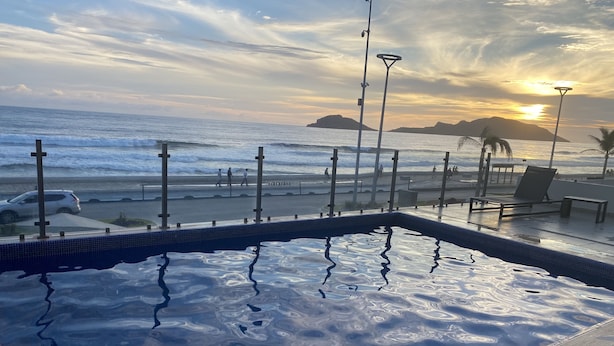 En swimmingpool med utsikt över havet och solnedgången.