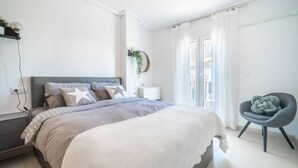 Een moderne slaapkamer met een bed, nachtkastje en stoel.