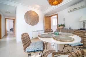 A dining area with a round table, wicker chairs, and a decorative wall piece.