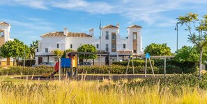 A residential area with white houses, a playground, and a clear sky.