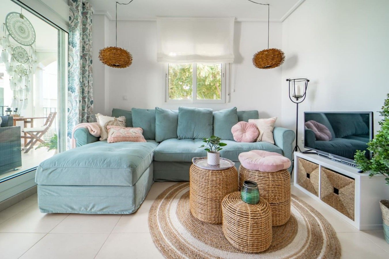 A modern living room with a sectional sofa, a flat-screen TV, and decorative wicker poufs.