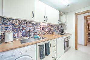 A kitchen with a washing machine, a coffee maker, and a tiled backsplash.