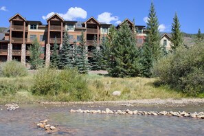 A multi-story lodge with balconies, surrounded by trees and a clear sky. - Walk to lift. Close to Lake. Hot Tub. Pool table (Keystone)