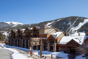Eine Lodge mit einer Steinfassade, hölzernen Balkonen und einem Schild mit der Aufschrift 'Hidden River Lodge'.