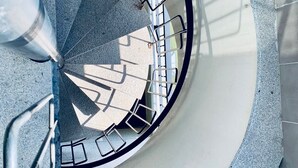 A spiral staircase with metal railings and a concrete floor, surrounded by white pebbles. - NON STRESS Duplex Penthouse with SEA views (Alboraya)