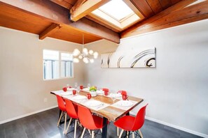 Enjoy meals in this dining area with a long table, exposed beams, and a skylight.