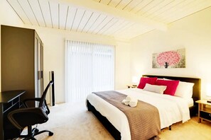 Relax in a stylish room with a large bed, flat-screen TV, and office chair.