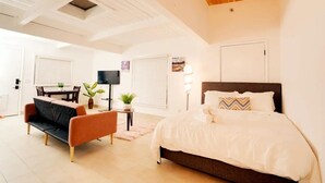 A modern bedroom with a large bed, a sofa, a TV, and a dining area with a table and chairs. - Luxe Studio Getaway in Mountain View Near Google! (Mountain View)
