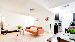 A modern living room with a sofa, coffee table, and a dining area with a table and chairs. - Luxe Studio Getaway in Mountain View Near Google! (Mountain View)