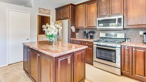 A kitchen with wooden cabinets, a granite countertop, stainless steel appliances, and a tiled backsplash.