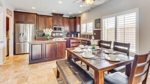 A modern kitchen with dark wooden cabinets, stainless steel appliances, and a dining area with a wooden table and chairs.