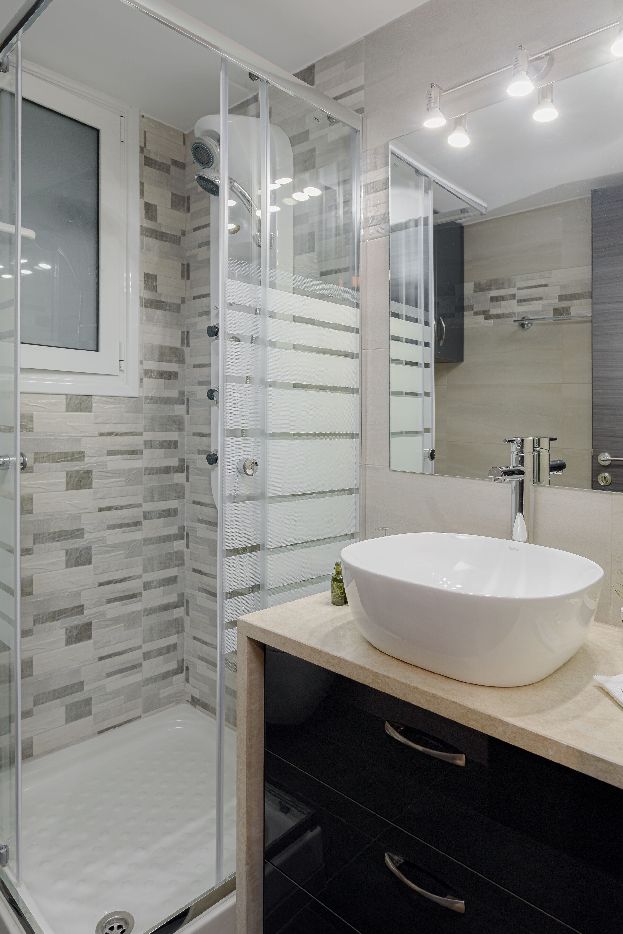 A modern bathroom with a glass-enclosed shower, a large white sink, and a mirror above it.